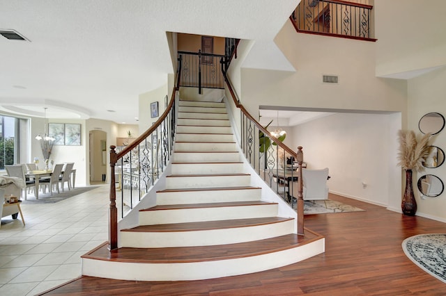 stairs with tile patterned flooring and an inviting chandelier