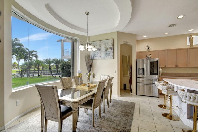 tiled dining room with an inviting chandelier and a tray ceiling