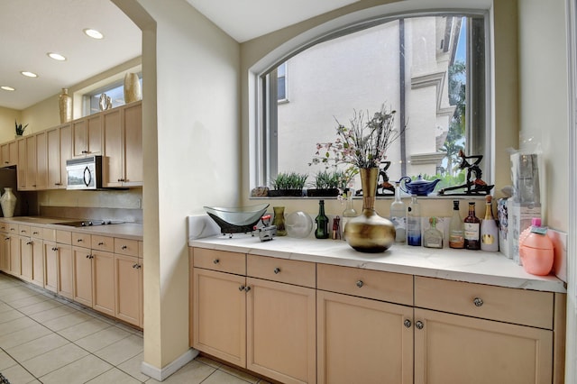 kitchen with light tile patterned floors, black electric stovetop, plenty of natural light, and light brown cabinets