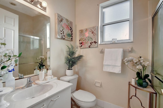 bathroom featuring a shower with door, vanity, and toilet