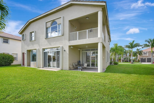 rear view of property with a balcony, a patio area, and a yard