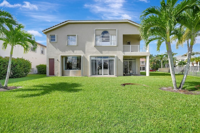 back of property with a balcony and a lawn