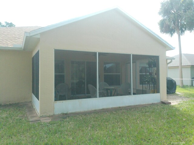 view of side of property with a lawn and a sunroom