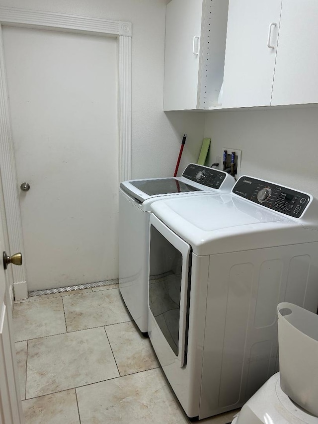 laundry room featuring washing machine and dryer, cabinets, and light tile patterned flooring