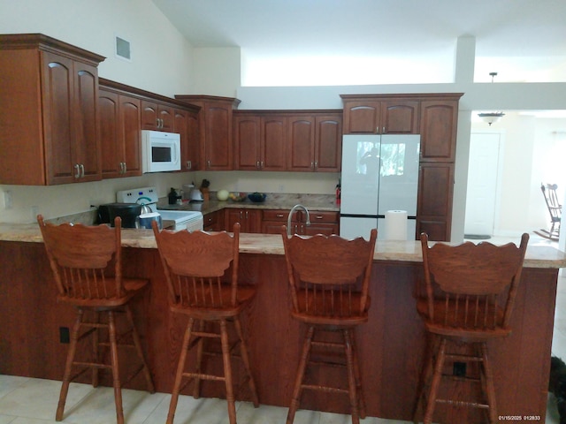 kitchen featuring high vaulted ceiling, a breakfast bar area, and white appliances