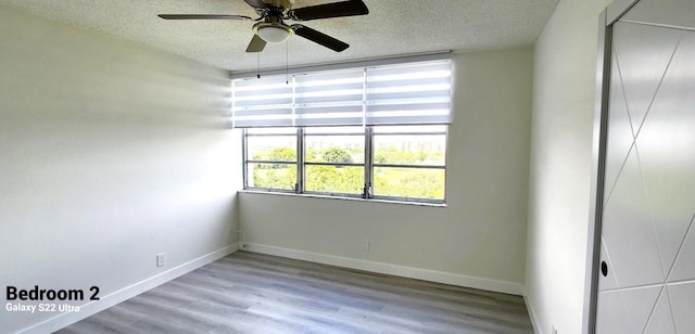 empty room with ceiling fan, light hardwood / wood-style floors, and a textured ceiling