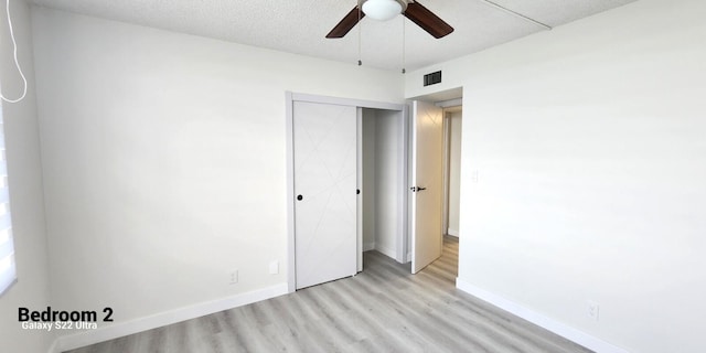 unfurnished bedroom with light hardwood / wood-style flooring, a closet, and ceiling fan