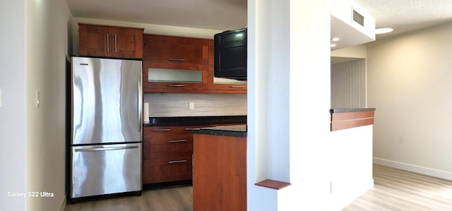 kitchen with tasteful backsplash, stainless steel fridge, a textured ceiling, and light hardwood / wood-style flooring