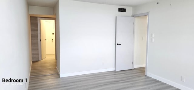 unfurnished bedroom with visible vents, baseboards, and wood finished floors