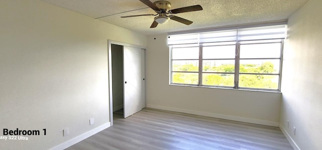 unfurnished bedroom with ceiling fan, a textured ceiling, a closet, and light hardwood / wood-style flooring