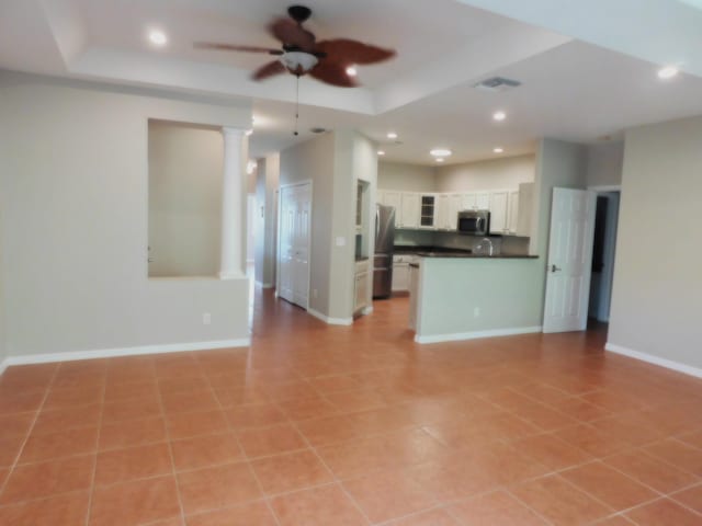 kitchen featuring white cabinets, a raised ceiling, ceiling fan, light tile patterned floors, and appliances with stainless steel finishes