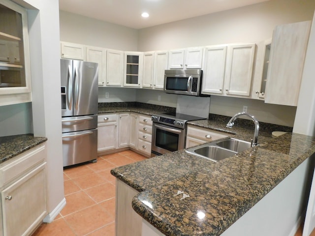 kitchen with white cabinets, dark stone counters, appliances with stainless steel finishes, and sink