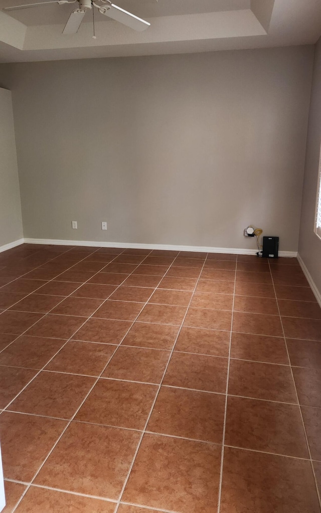 spare room with dark tile patterned floors and a tray ceiling