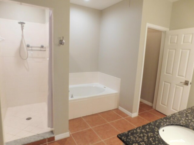 bathroom with independent shower and bath, sink, and tile patterned floors