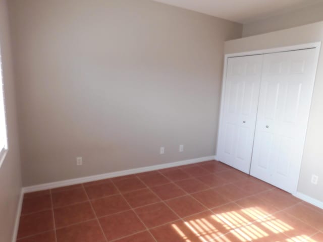 unfurnished bedroom with tile patterned flooring and a closet