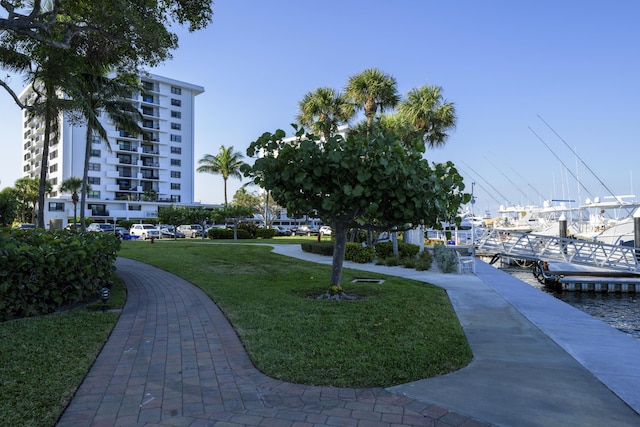 view of community featuring a water view, a dock, and a lawn