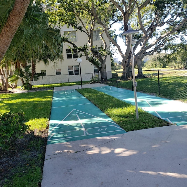 view of home's community featuring fence, a lawn, and shuffleboard