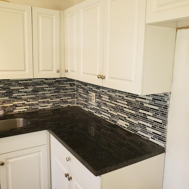 kitchen with tasteful backsplash, a sink, and white cabinets