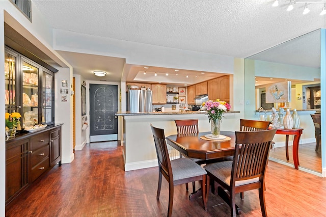 dining space featuring wood-type flooring and a textured ceiling