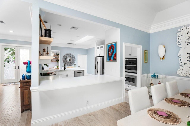 kitchen featuring light wood-type flooring, white cabinets, kitchen peninsula, and appliances with stainless steel finishes