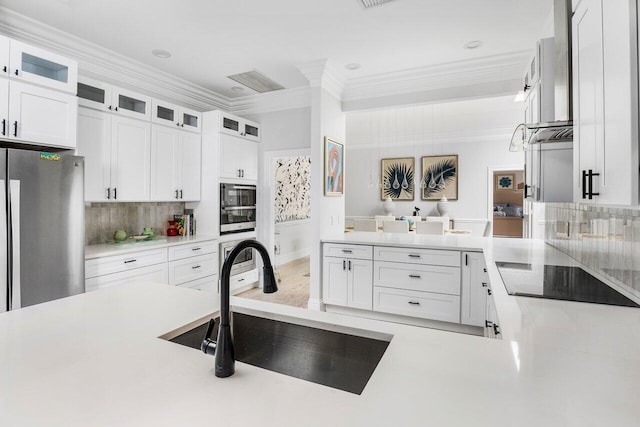 kitchen with white cabinetry, stainless steel fridge, black electric stovetop, crown molding, and sink