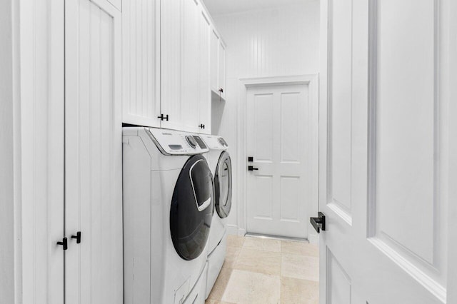 clothes washing area featuring separate washer and dryer and cabinets