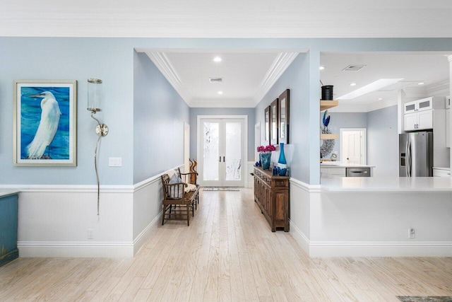 interior space with white cabinetry, stainless steel appliances, french doors, crown molding, and light hardwood / wood-style flooring