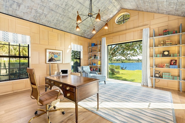 office space featuring a wealth of natural light, high vaulted ceiling, wood finished floors, and a water view