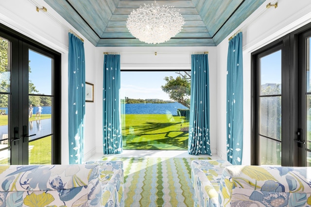 bedroom with french doors, a water view, a chandelier, and ornamental molding