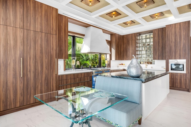 kitchen with stainless steel appliances, coffered ceiling, wood walls, and custom range hood