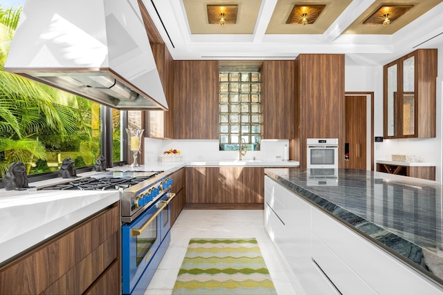 kitchen with oven, beamed ceiling, range with two ovens, range hood, and modern cabinets