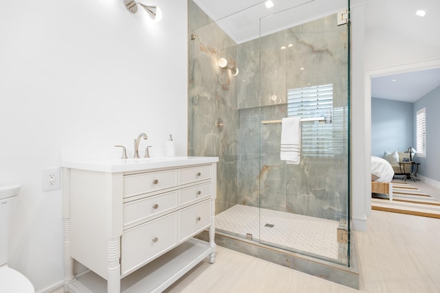 ensuite bathroom featuring a marble finish shower, baseboards, toilet, and vanity