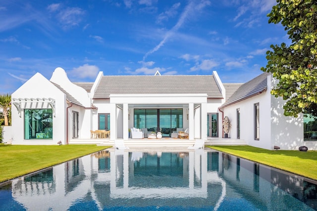 rear view of property featuring stucco siding, a yard, a pergola, and an outdoor hangout area