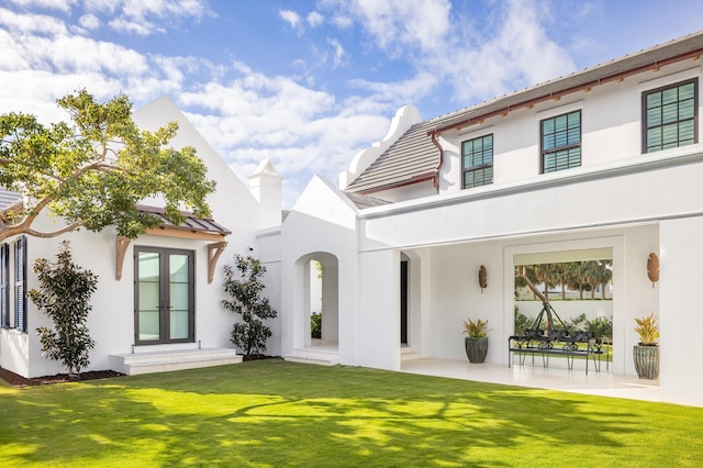 back of property featuring french doors, a yard, and a patio area