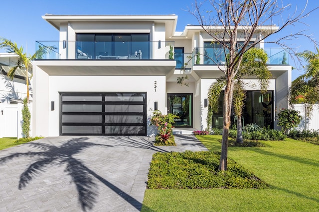 contemporary house featuring a balcony, a front yard, and a garage