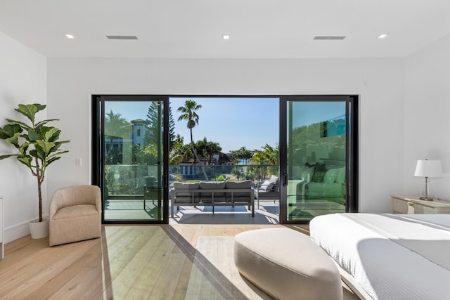 bedroom with light hardwood / wood-style floors, access to exterior, and multiple windows