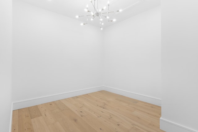 spare room featuring an inviting chandelier and wood-type flooring