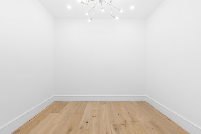 unfurnished room with hardwood / wood-style flooring and a notable chandelier