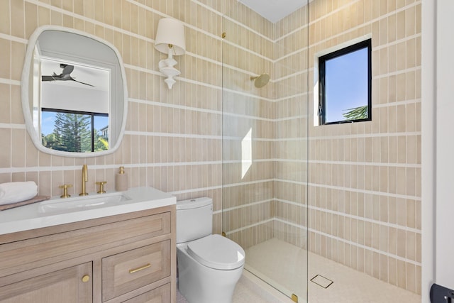 bathroom with tile walls, a tile shower, vanity, and toilet