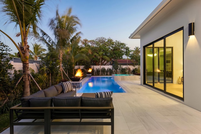 pool at dusk with outdoor lounge area and a patio