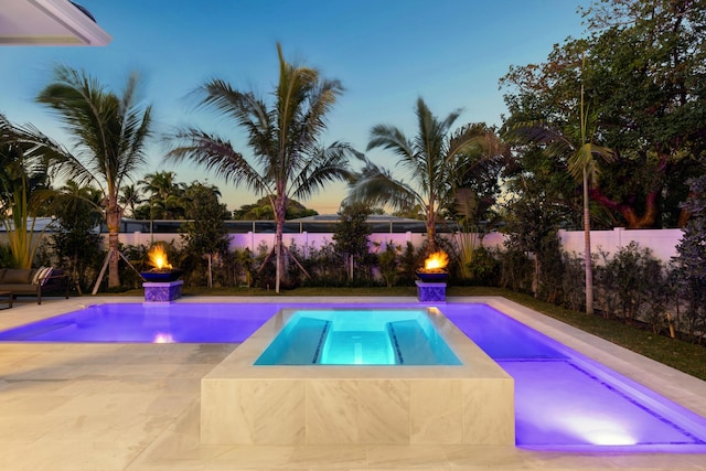 pool at dusk with a jacuzzi and a patio area