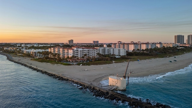 aerial view at dusk featuring a beach view and a water view