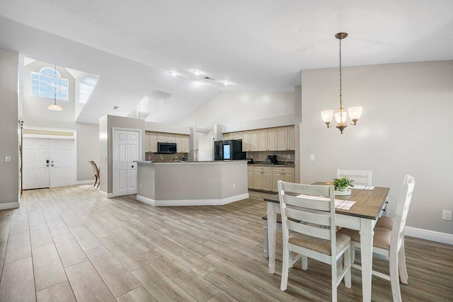 kitchen featuring light hardwood / wood-style floors, black fridge, high vaulted ceiling, cream cabinets, and an inviting chandelier