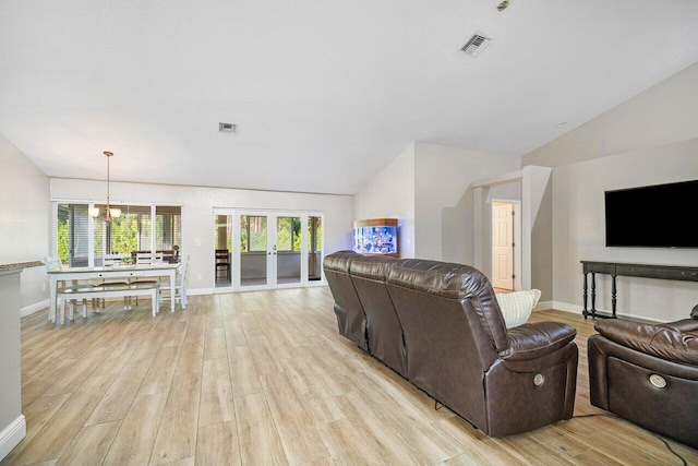 living room featuring lofted ceiling, a notable chandelier, and light hardwood / wood-style floors