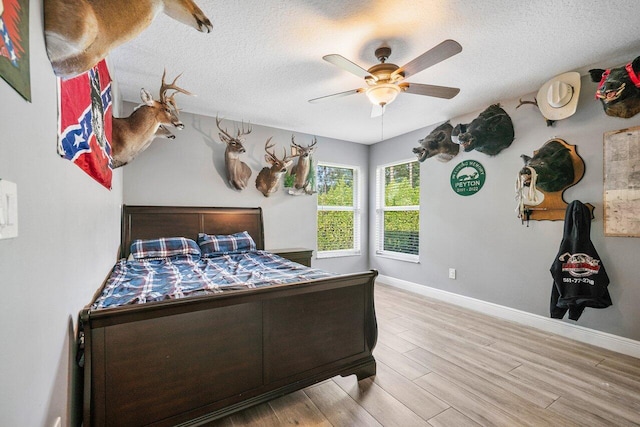 bedroom with a textured ceiling, ceiling fan, and light hardwood / wood-style flooring