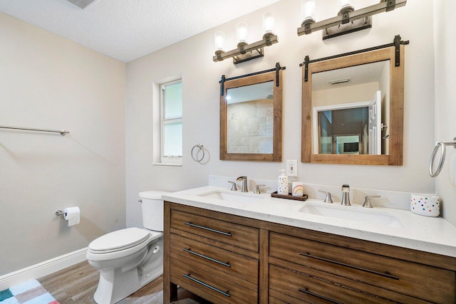 bathroom with toilet, vanity, a textured ceiling, and hardwood / wood-style floors