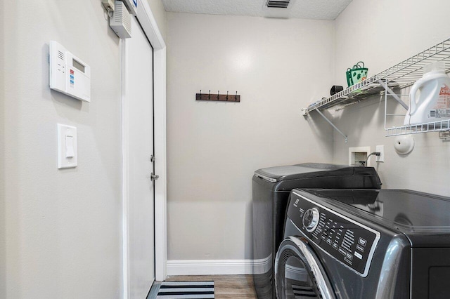 laundry area with a textured ceiling, washing machine and clothes dryer, and hardwood / wood-style flooring