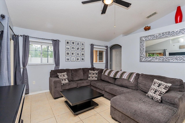 living room with lofted ceiling, light tile patterned flooring, a textured ceiling, and ceiling fan