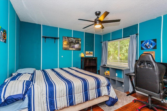 bedroom with a textured ceiling, ceiling fan, and wood-type flooring