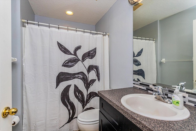 bathroom with a textured ceiling, backsplash, vanity, and toilet